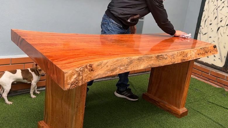 Man polishing vibrant live edge teak wood table