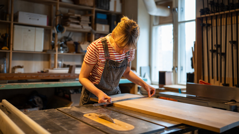 young blonde woman measuring wood boards