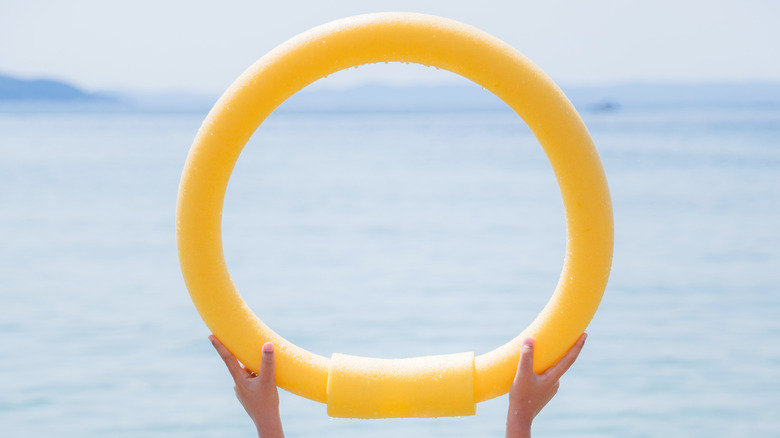 woman holding round pool noodle