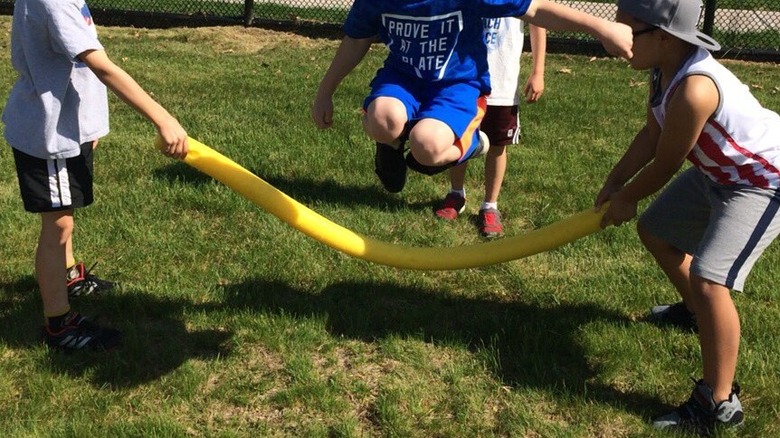 kid jumping over pool noodle