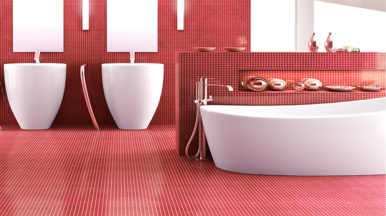 A bathroom covered in red tile with a white bathtub and white sinks