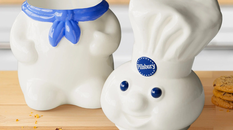 2025 pillsbury doughboy cookie jar on a counter next to cookies and a glass of milk