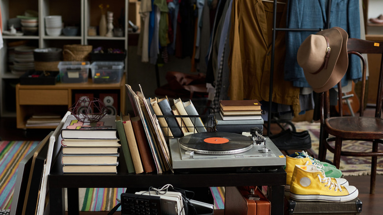 A thrift store cart with books, a record player, and yellow Converse sneakers displayed on it