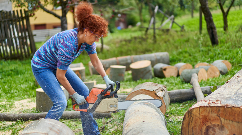 A woman with a chainsaw cutting a tree log