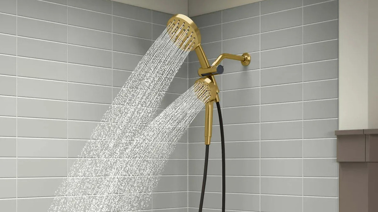 The Kohler Prone 3-in-1 Multifunction Shower Head in gold in a tiled shower