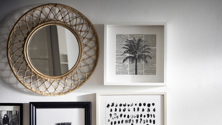 A GRINSBOL mirror from IKEA hangs next to a framed tropical palm tree print