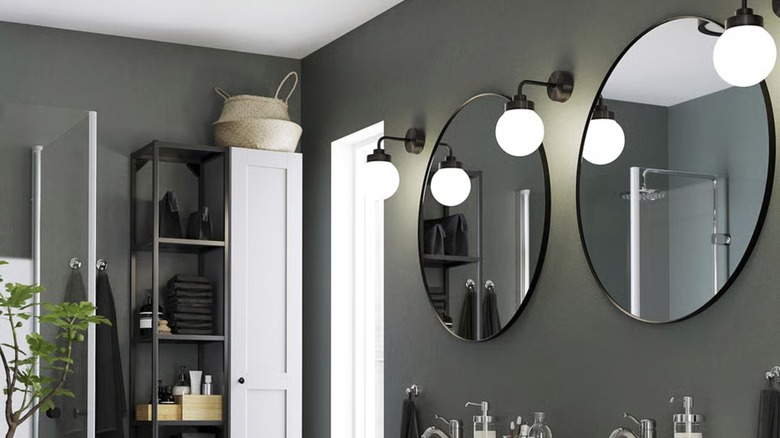 Two black LINDBYN mirrors hang next to globe sconces in a gray bathroom