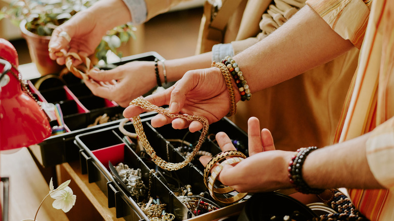 Close-up of hands picking up jewelry from box