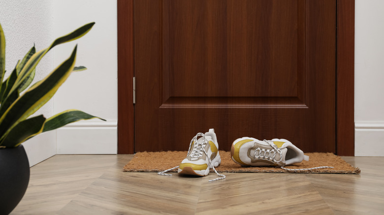White and yellow sneakers on door mat