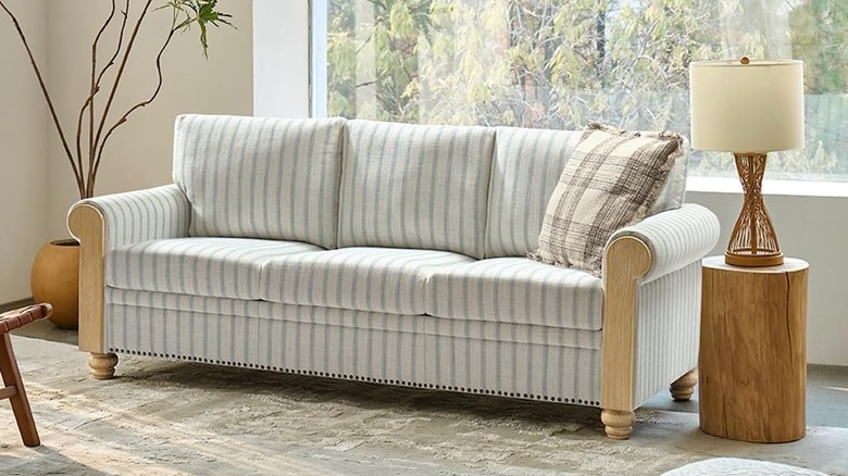 A white and light blue striped sofa with wood paneling on the sides