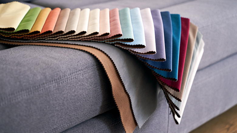 A close-up of a couch in a showroom with different fabric swatches draped over it