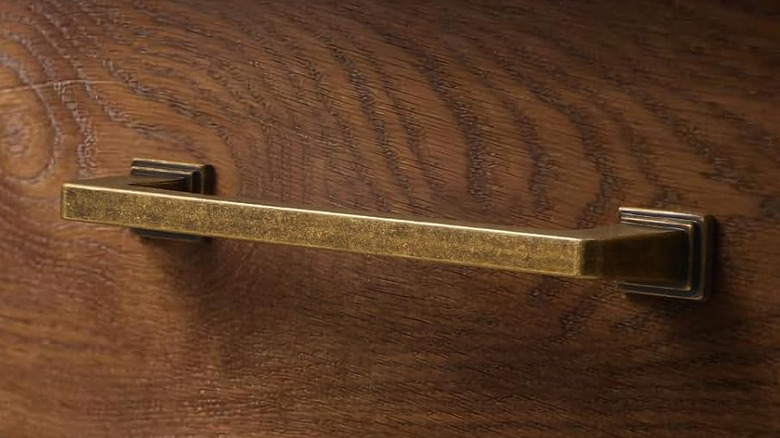 A SORWDUERM Antique Brass Cabinet Pull is installed on a warm walnut stained wooden drawer