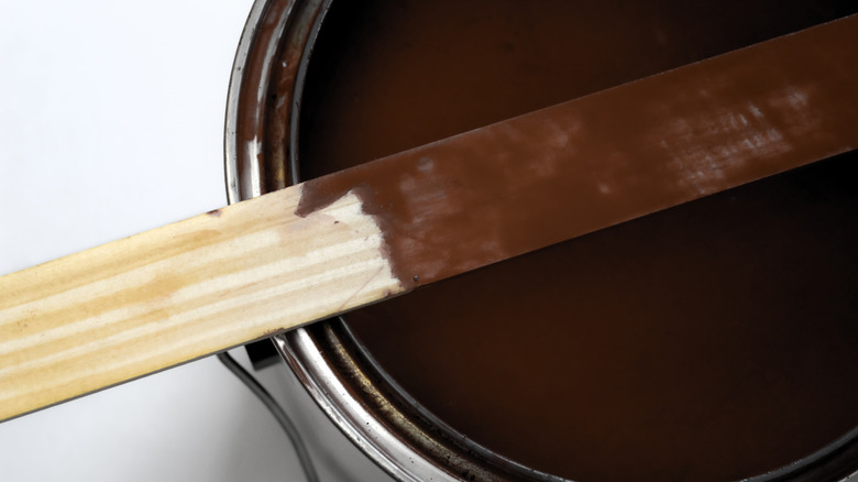 A stirring stick has been partially submerged in a can of stain