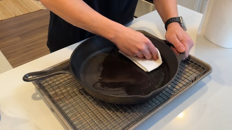 Man adds oil to cast iron skillet to season it