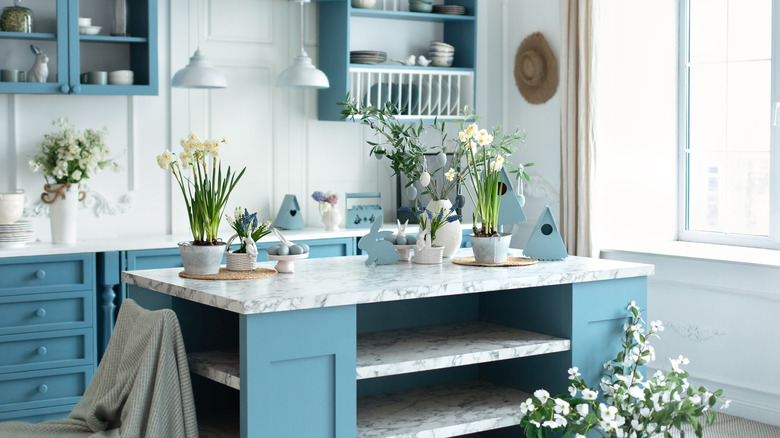 White kitchen with light blue cabinets, white flowers, and light blue accents and decor on the counters
