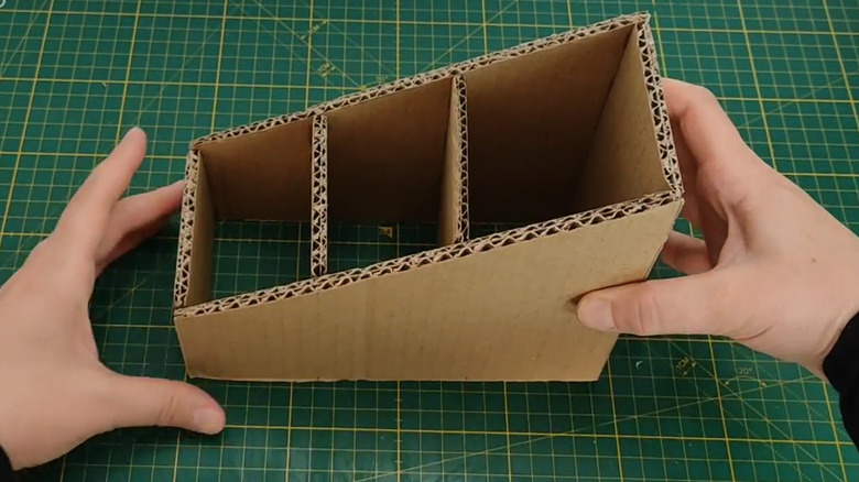Person making DIY cardboard TV remote holder
