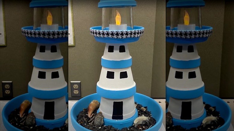 A completed DIY lighthouse birdfeeder in blue and white, with seeds and seashells