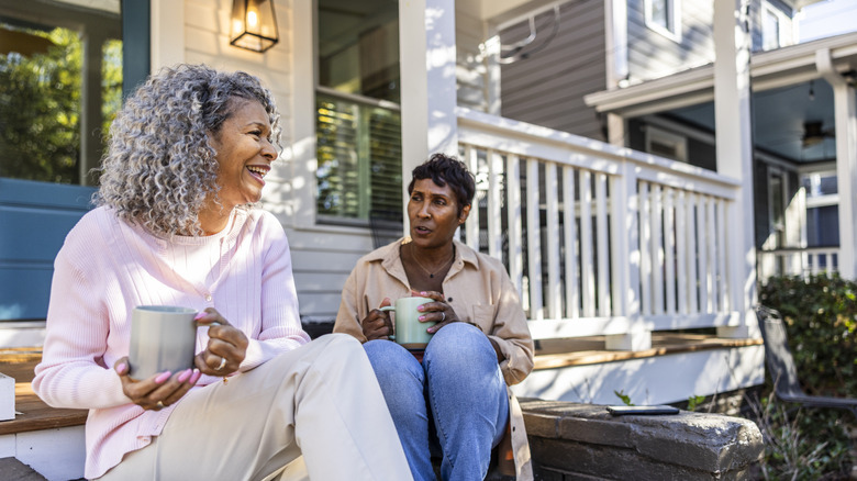 Women chatting while drinking coffee on front porch