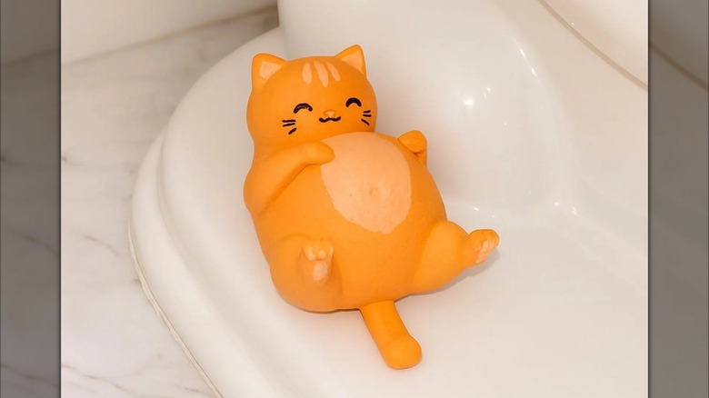 A smiling orange cat lying on its back as a bolt cover
