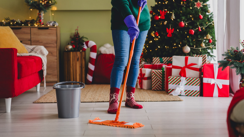 A person cleaning floors with Christmas decorations and presents in background