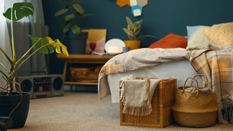 Large woven baskets sit at the foot of a bed with blankets and sheets peeking out of them.
