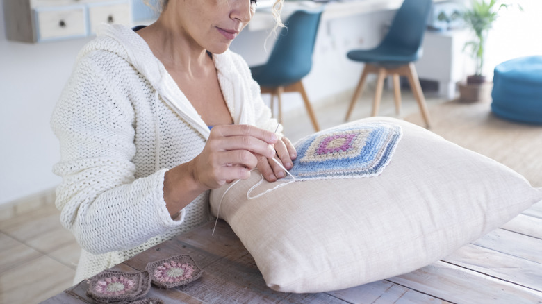 A person creating a custom pillow case using crochet granny squares