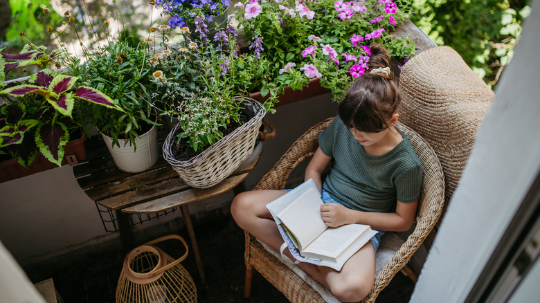 Woman sits on her balcony reading a book
