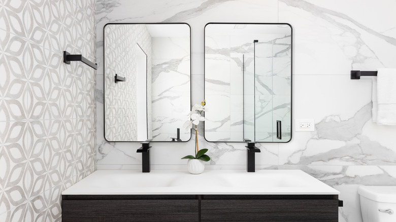 A white and black bathroom with two mirrors.