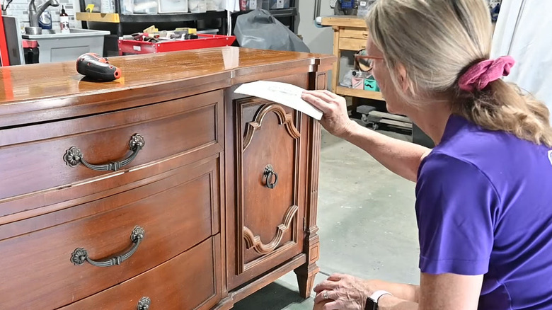 Person sliding cardstock through the gap of a cabinet door