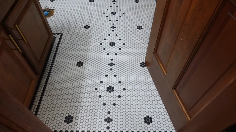 A close-up view of a bathroom floor featuring round penny tiles in white with black patterns