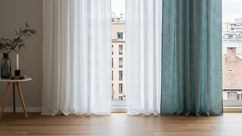 White and blue drapes hanging in window with city view