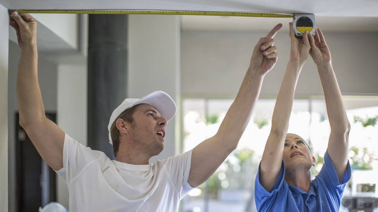 Man and woman measuring ceiling