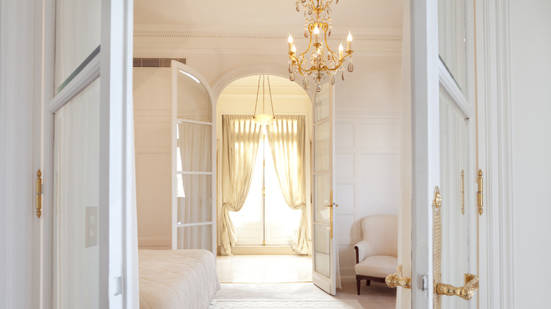 A chandelier illuminates a neutral bedroom