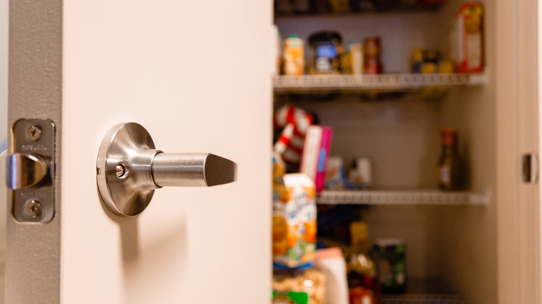 An open pantry door with blurred food packages in the back