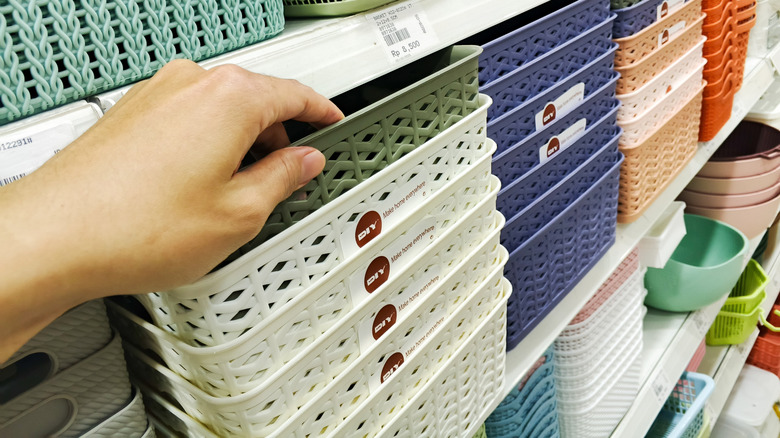 Hand reaching for plastic home organizer basket on shelf