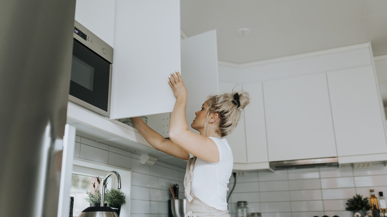 Woman opening a kitchen cabinet