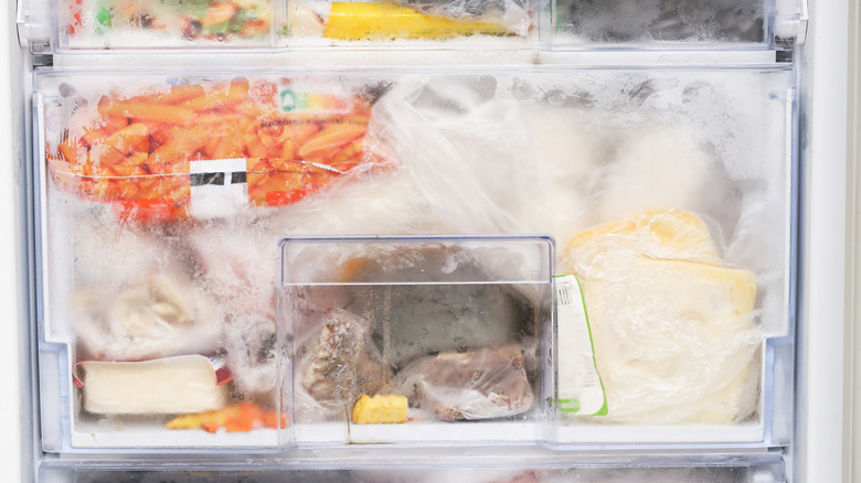 A cluttered and iced-up freezer drawer.