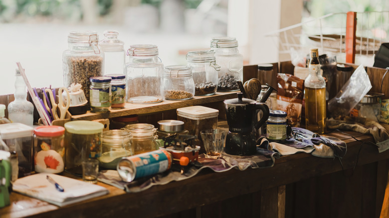 Cluttered kitchen countertop with jars, bowls, and other storage scattered