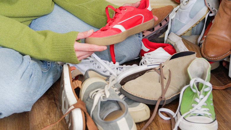 Person going through messy pile of shoes on the floor