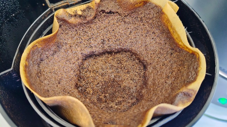 Used coffee grounds are left over in a paper filter.
