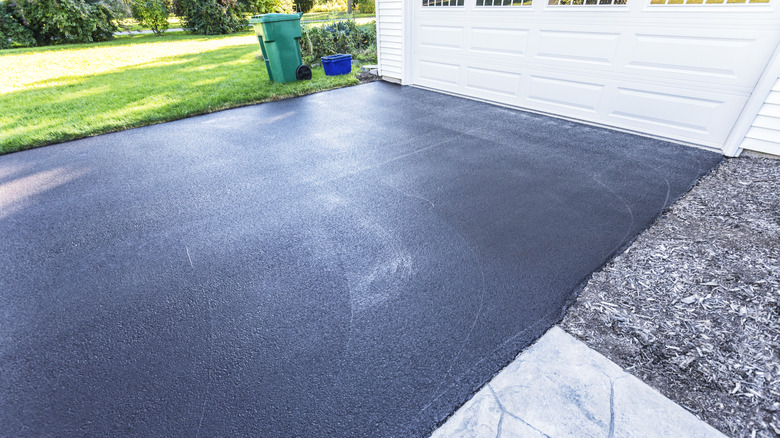 An asphalt driveway in front of a white garage door.