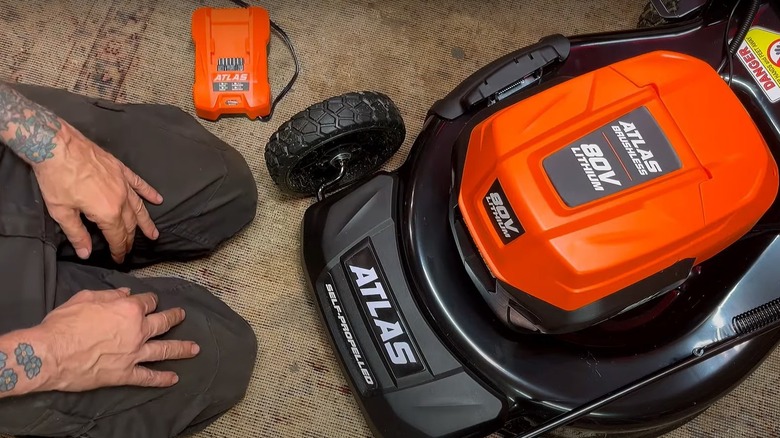 Person kneeling beside Atlas lawn mower