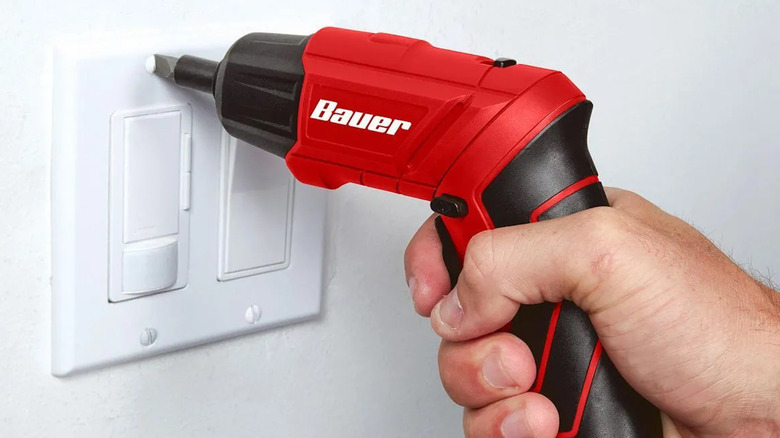 person using the Bauer 1/4-inch cordless electric screwdriver to install light switch cover
