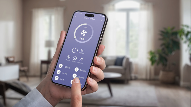 A woman uses a smartphone to adjust the settings of a smart home device.