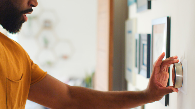 A man adjusting the thermostat in his home