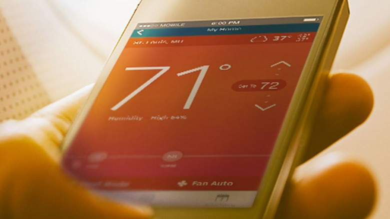 A hand holding a phone open to the Sensi app for their smart thermometer