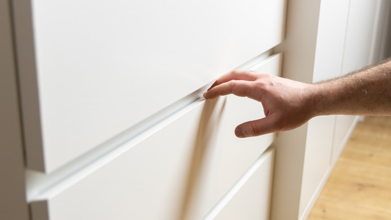 Someone about to open a white dresser drawer