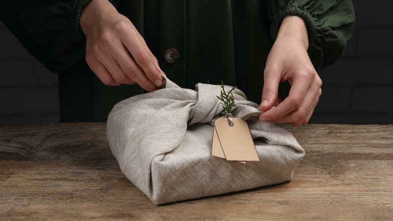 Hands tying fabric into understated reusable wrapping paper