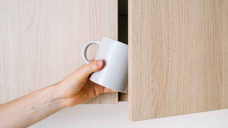 Person grabbing a mug out of a cabinet