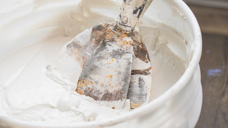 A gloved hand holding a trowel against a white background.